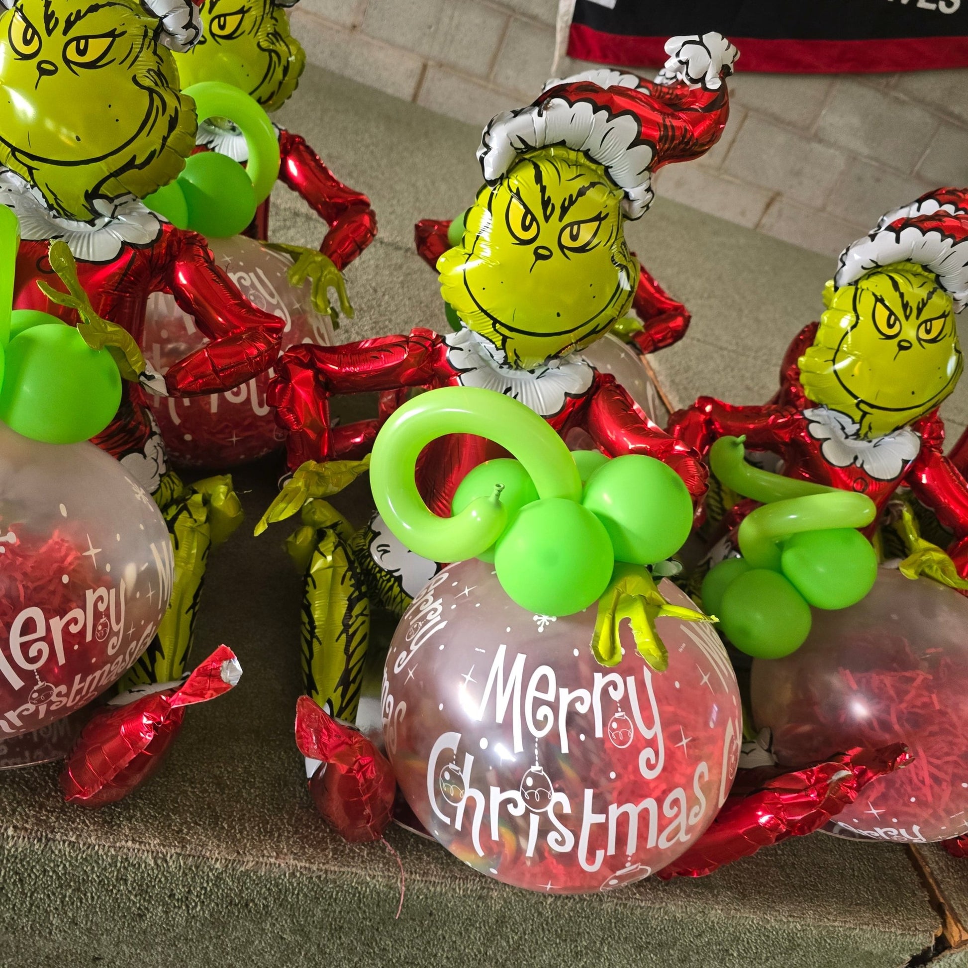 Grinch Sitting with a Merry Christmas "POP" Balloon with 24 Candy Canes Stuffed inside - UpUpNAwayBalloons